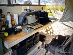 outdoor office setup under expansive awning of off-road camping trailer in desert environment